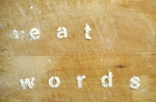 Picture of the words Eat Words made in flour on a wooden board