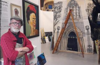 Artist John McDonald standing in front of his artwork exhibition